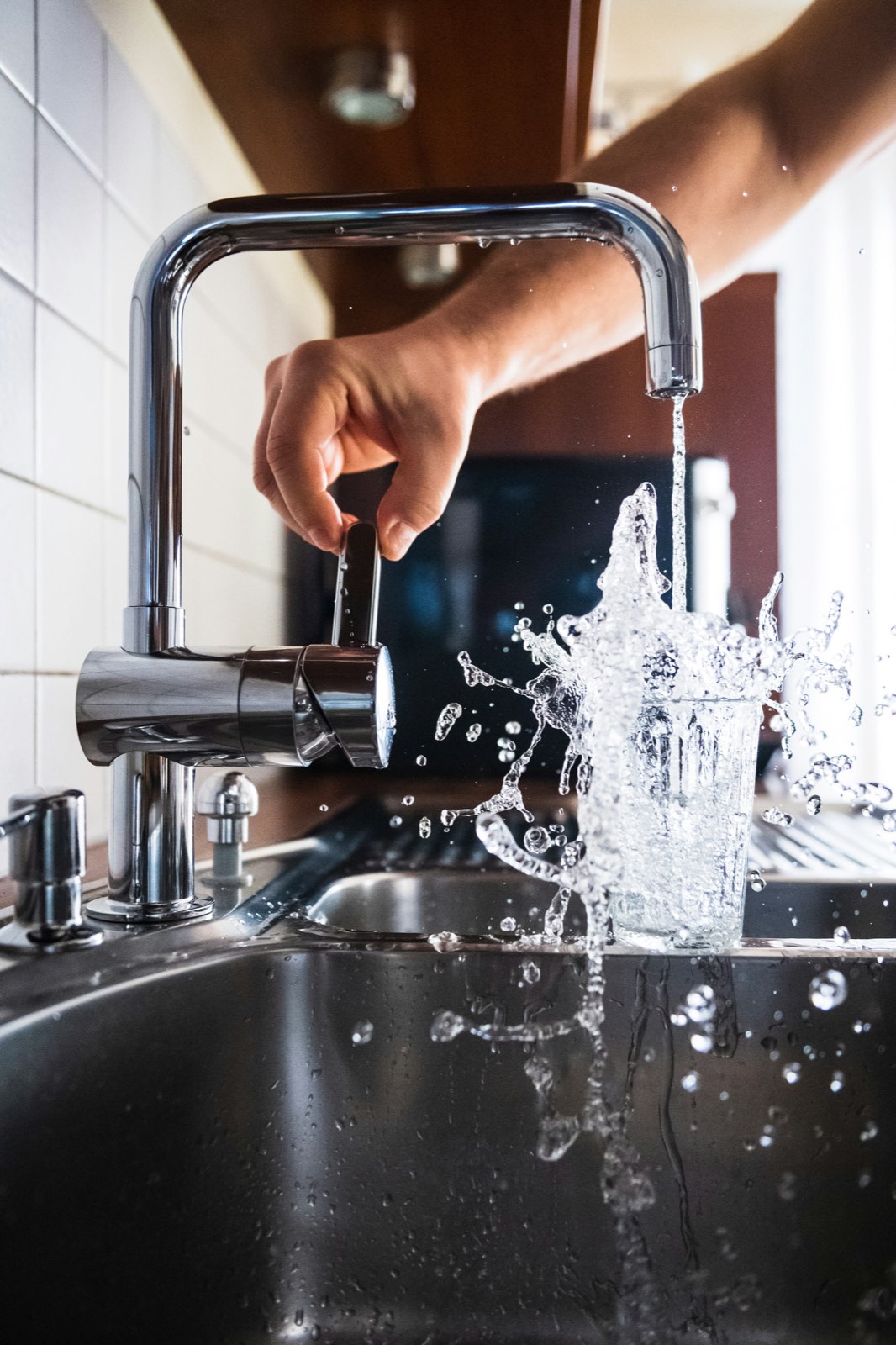 Glass being filled with water at a kitchen faucet